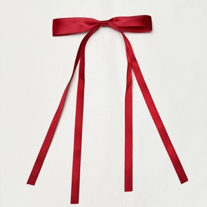 Detail of red polyester satin hair bow with long ribbons on white background
