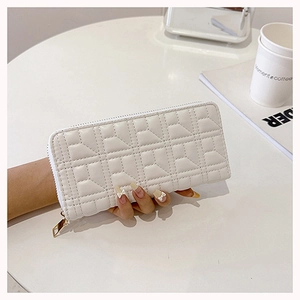 Close-up of white quilted PU leather long wallet with gold zipper on a coffee table