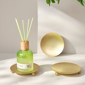Golden round metal display tray set with luxury green aromatherapy diffuser bottle
