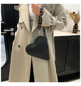 Detail of black heart clutch in lychee leather with a colorful LOVE printed wrist strap