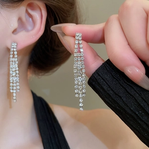 Gros plan de boucles d'oreilles de mariée en argent avec pompons en zircon et design long