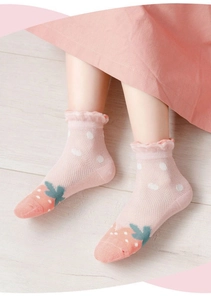 Vue détaillée de chaussettes bébé en maille rose avec fraises et revers en dentelle