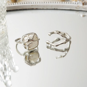 2-piece set of irregular liquid metal rings with faux pearls on a mirrored surface