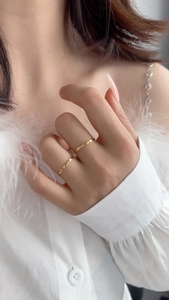 Close-up of dual minimalist gold stackable rings worn by a model on a white background