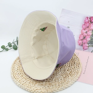 Detail of purple bucket hat featuring green cactus embroidery and beige cotton lining