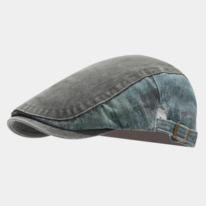 Detail view of the distressed patchwork denim flat cap with adjustable bronze buckle