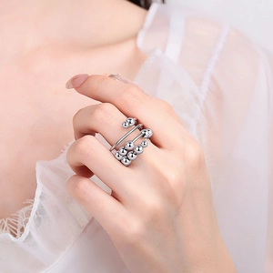 Three-layer silver fidget ring with rotating beads on a hand model in white lace