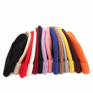 Flat lay of thick ribbed knit beanies in 14 vibrant colors with folded cuffs for winter