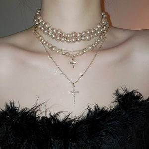 Detail of layered gold necklaces with pearl strands and sparkling crystal cross pendants