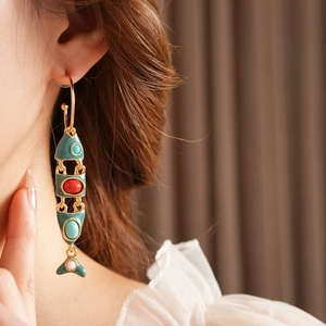 Detail of vintage enamel fish earring with gold finish and colorful gemstones