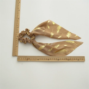 Khaki chiffon hair scrunchie with gold feather print and streamers measured on white background
