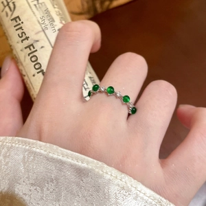 Close-up of a silver ring with green agate beads and white zircon wave setting