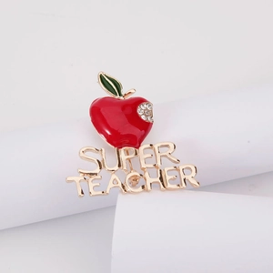 Détail macro d'une broche pomme en émail rouge avec strass et texte Super Teacher