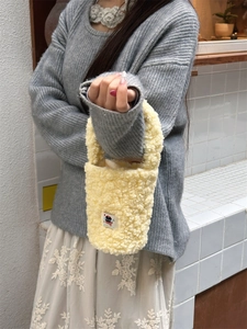 Close-up of fluffy yellow sherpa fleece tumbler bag with cartoon patch and handle