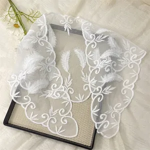 Close-up of white lace floral embroidery on high-quality mesh fabric with feather patterns