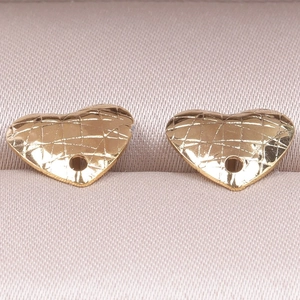 Macro shot of gold heart-shaped pendants with quilted diamond texture and hanging holes