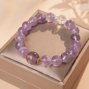 Detail of amethyst beaded bracelet with gold accents on champagne satin jewelry box
