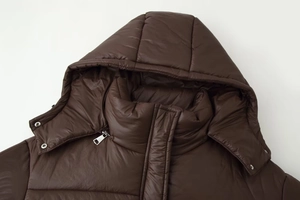 Détail d'un manteau doudoune marron café avec col montant à capuche et boutons-pression