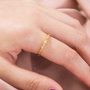 Elegant gold ring with round center stone and tiny cubic zirconia on a female finger