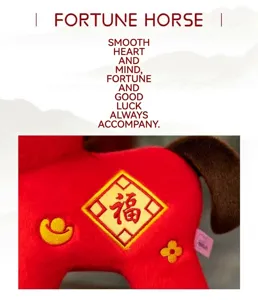 Close-up detail of a red plush horse zodiac mascot with gold 'Fortune' embroidery