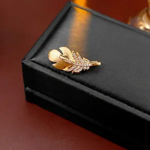 Elegant gold feather brooch with brushed metal texture and sparkling zircon crystals