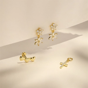 Macro shot of gold flower earrings and heart studs set with white zircon stones