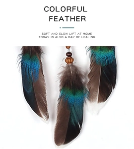 Close-up of bohemian dream catcher with iridescent peacock green and brown feathers
