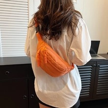 Bolso de lona naranja para mujer sobre camisa blanca con correa de cadena de moda