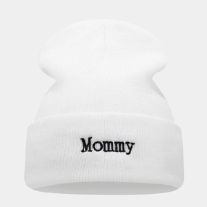 Close-up of black 'Mommy' embroidery on a white knitted beanie with folded cuff