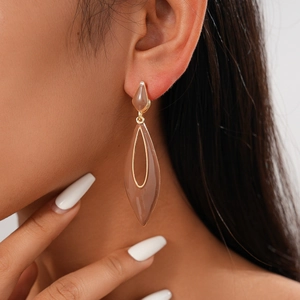 Detail shot of vintage hollow teardrop earrings with gold trim and beige resin on model