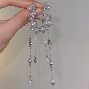 Close-up of sparkling tassel earrings with zirconia crystals and faux pearls details