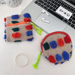 Macro shot of colorful plush mini storage bags with soft faux fur texture and pom-poms