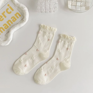 Detail of white knit socks with pink heart dots and delicate ruffle cuffs for women