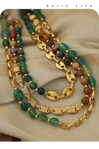 Macro detail of retro copper pig nose chains with natural agate beads on beige silk cloth