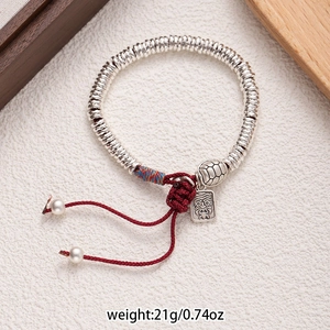 Macro shot of ethnic braided bracelet with silver metal beads and turtle pendant
