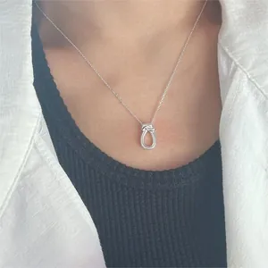 Detail of S925 sterling silver knot pendant necklace worn on neck with minimalist chain
