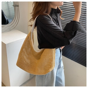 Macro detail of the woven texture on a beige shoulder bag worn by a model in casual attire