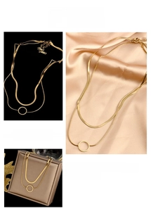Close-up of double-layer snake chain necklace with hollow round pendant in gold finish