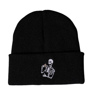 Detailed close-up of embroidered skeleton drinking coffee on black knit beanie