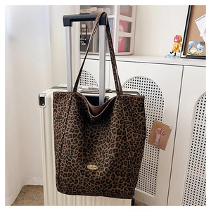 Leopard print canvas tote bag hanging on white suitcase handle in a cozy home interior