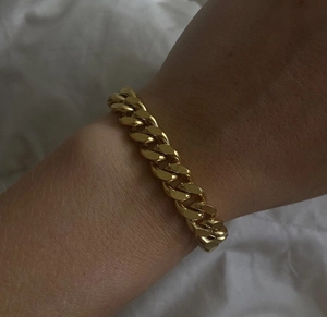 Detailed close-up of 18k gold-plated Cuban link chain bracelet on wrist with mirror finish