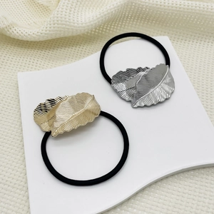 Detail of alloy leaf charms on black elastic hair ties in gold and silver finish