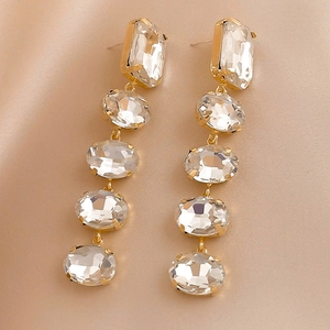 Macro detail of luxury long fringe earrings with crystals on champagne silk fabric