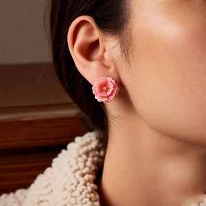 Close-up of pink layered resin flower earrings with golden stamen on a female model