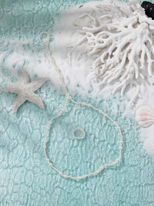 Double-layer pearl beach anklet set on white sand with coral and seashell accents