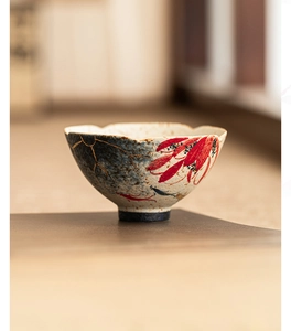 Detailed close-up of hand-painted red flower and gold texture on ceramic teacup