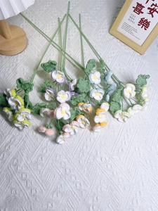 Detail of handmade crochet pansy bouquet with colorful yarn flowers on white fabric
