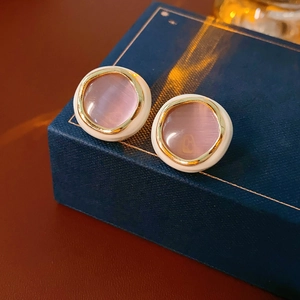 Detailed macro view of vintage round earrings with pink stone and golden metal rim