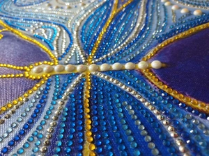 Macro detail of 5D diamond painting showing sparkling blue and gold butterfly rhinestones