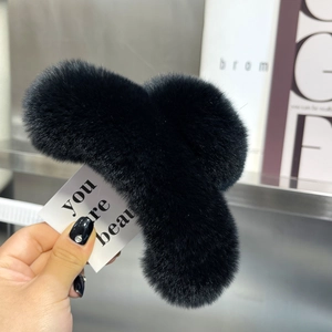 Close-up of a large black plush claw clip with soft faux fur texture for women